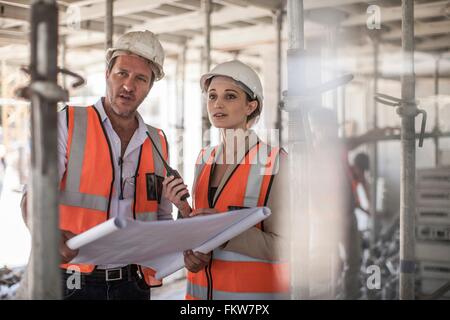 Female and male builders with blueprint on construction site Stock Photo