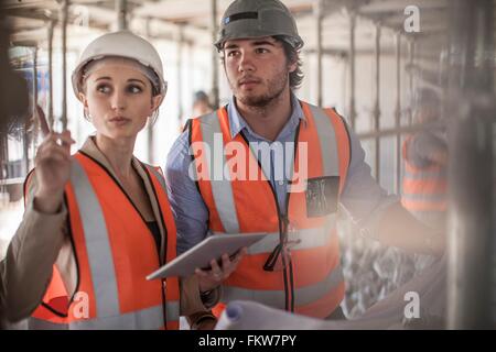 Female and male builders using digital tablet on construction site Stock Photo