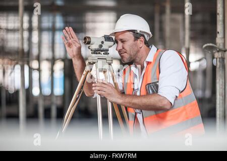 Male surveyor looking through theodolite on construction site Stock Photo