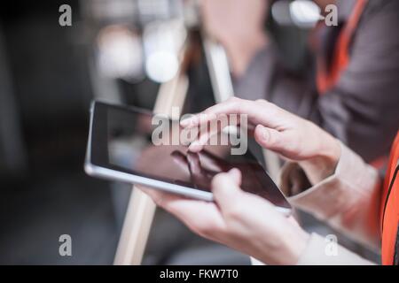 Close up of female surveyor using tablet touchscreen on construction site Stock Photo