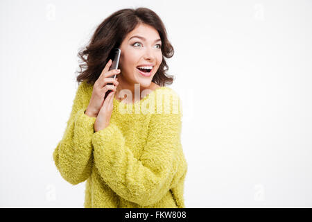 Surprised woman covering microphone while talking on the phone and looking away isolated on a white background Stock Photo