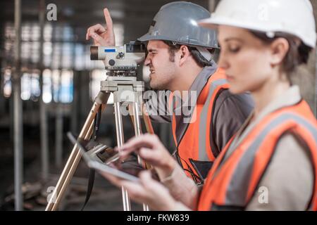 Female and male surveyor using digital tablet and theodolite  on construction site Stock Photo