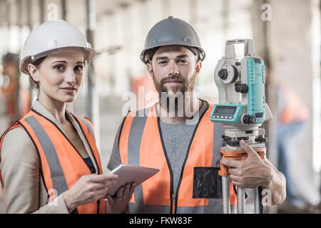Portrait of young male and female surveyors on construction site Stock Photo