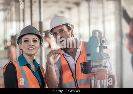 Surveyor explaining to female builder on construction site Stock Photo