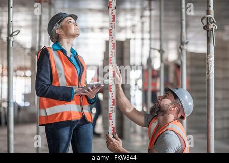 Young male and female builders measuring construction with ruler Stock Photo