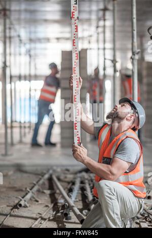 Young male builder measuring construction with ruler Stock Photo