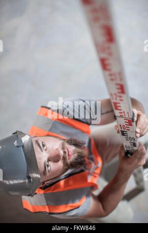 High angle view of young male builder measuring with ruler Stock Photo