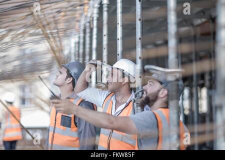Site manager and builders looking up at steel rod structure on  construction site Stock Photo