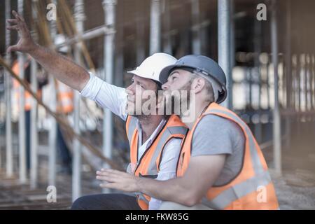 Site manager and builder looking up at steel rods on  construction site Stock Photo