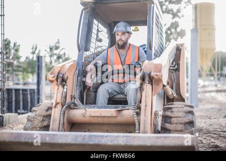 Builder driving excavator on construction site Stock Photo