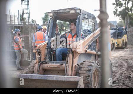 Construction worker driving excavator on construction site Stock Photo