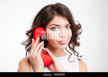 Young woman covering microphone on phone tube and looking at camera isolated on a white background Stock Photo