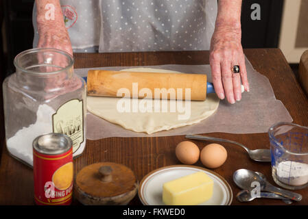 Close-up of a woman rolling out pie dough in a 1930's period kitchen. Stock Photo