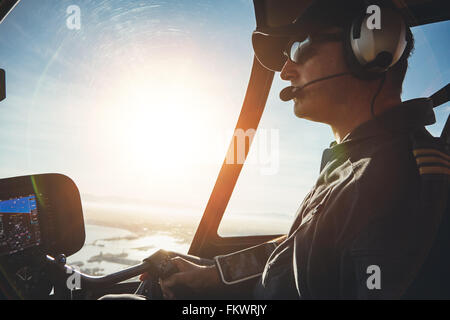 Close up of a pilot flying a helicopter with sun flare entering the cockpit. Stock Photo