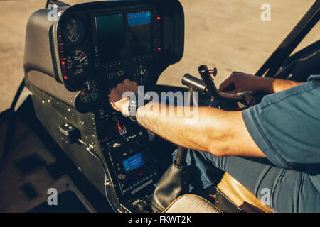 Close up shot of pilot checking the gauges on the instrument panel dashboard of  a helicopter. Pilot's hand on an helicopter ins Stock Photo