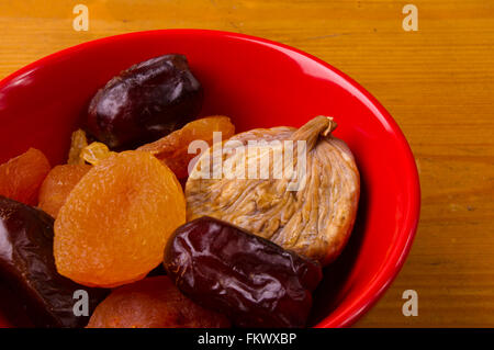 various dried fruits in red plate on wooden background Stock Photo