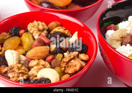 various different mixed nuts and raisins in red plate on white background Stock Photo