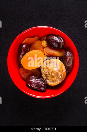 various dried fruits in red plate on the black background Stock Photo