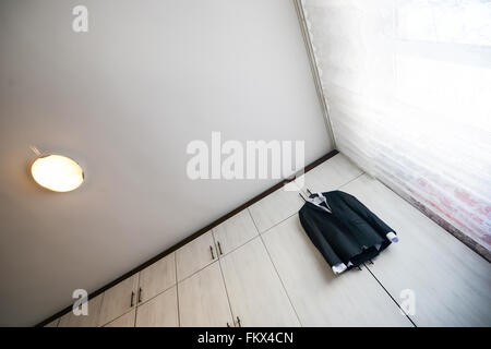 Black suit with shirt hanging from a wooden cupboard Stock Photo