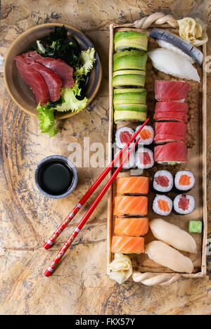 Sushi set nigiri, sashimi and rolls on clay plate served with chopsticks and soy sauce on stone surface. Flat lay. Stock Photo
