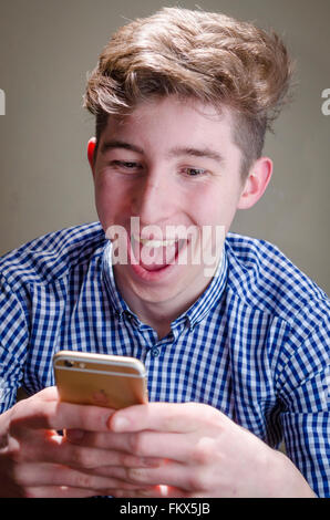 Young Man Using Smart Phone and Laughing Stock Photo