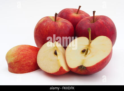 Four red Gala apples with one sliced in half and quarters showing the core, isolated on a white background. Stock Photo