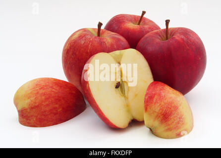 Four red Gala apples with one sliced in half and quarters showing the core, isolated on a white background. Stock Photo