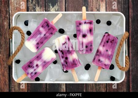 Group of blueberry vanilla ice pops in a vintage ice tray with rustic wood background Stock Photo