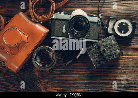 Old film camera, lenses and old exposure meter on a wooden background Stock Photo