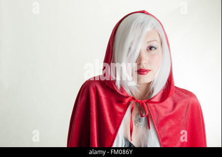 young lady in red hooded cape and wolf shadow on wall Stock Photo