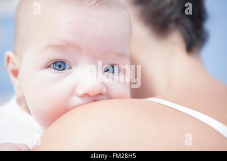 Portrait of a four months old baby over his mom's shoulder Stock Photo