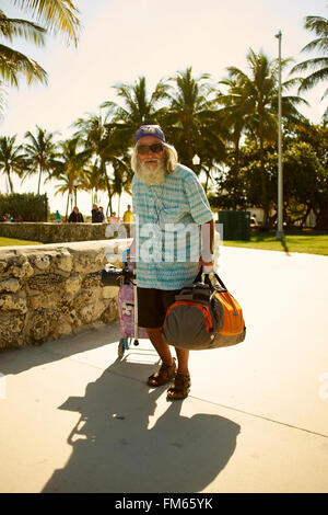 Old Man with Beard carrying a bag and pulls a hack Porsche Stock Photo