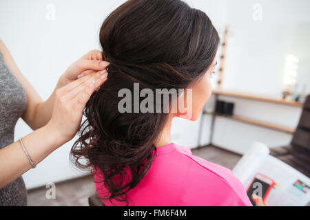 Back view of hairstyle of young woman with curly dark hair made by female hair stylist in beauty salon Stock Photo