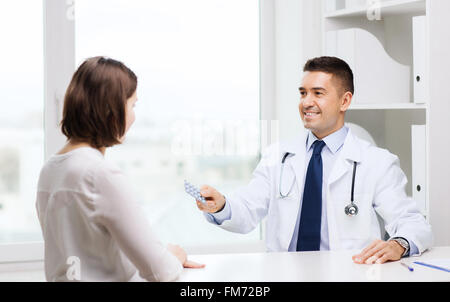 smiling doctor giving pills to woman at hospital Stock Photo