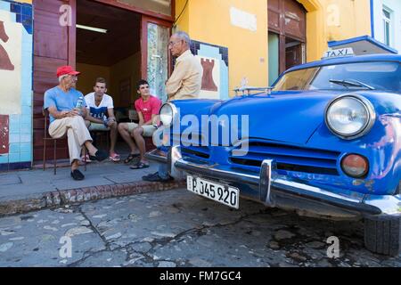 Cuba, Sancti Spiritus Province, Trinidad de Cuba listed as World Heritage by UNESCO, people sitting by the chess club and american car Stock Photo