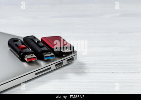 Three thumb drives with different colors inside for USB technologies. Computer and desktop in background. Stock Photo