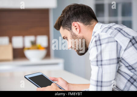 Young man using digital tablet while leaning on table Stock Photo