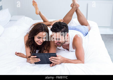 Smiling couple using digital tablet while lying under blanket Stock Photo