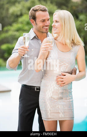 Smiling couple holding champagne flutes at poolside Stock Photo