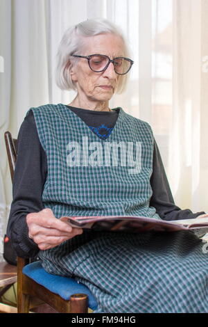 Ninety years old lady reading newspapers indoors Stock Photo