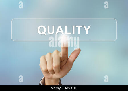 business hand pushing quality button on blurred background Stock Photo