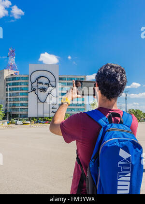 A young adult male tourist takes a photo with a digital tablet of the revolutionary guerrilla fighter Camilo Cienfuegos. Stock Photo