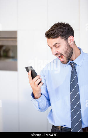 Businessman shouting while looking in mobile phone Stock Photo