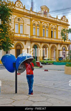 Cuba, Ciego de Avila, Morón, Man phoning in a booth in front of a colonial-style building Stock Photo