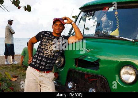 Cuba, Guantanamo, Baracoa, Young man leaning on the bonnet of his van Stock Photo