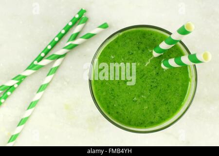 Green smoothie downward view in glass with straws on white marble background Stock Photo