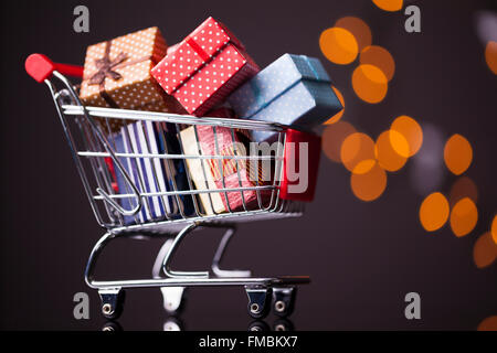 Shooping cart full of gift boxes on dark background Stock Photo