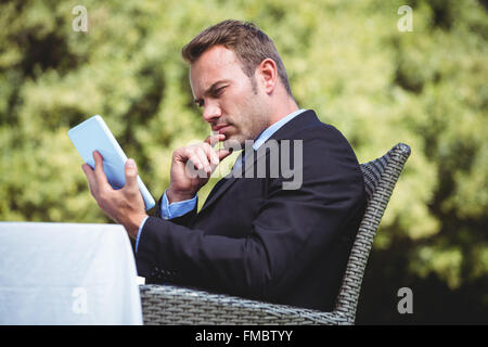 Thoughtful businessman using tablet Stock Photo