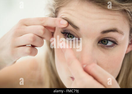 Close-up of young woman applying contact lens