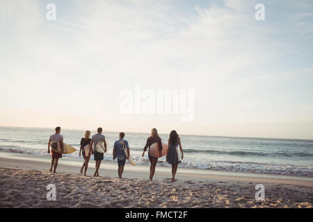 Happy friends walking with surfboards